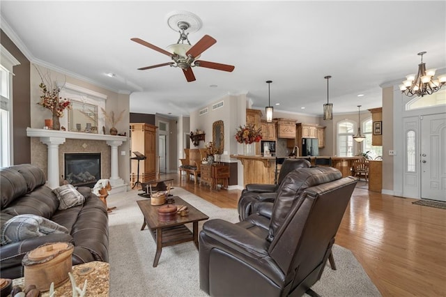 4148 SE Paddock Dr, Lees Summit, MO 64082 - living room featuring a chandelier, light wood-style floors, ceiling fan, ornamental molding, and a glass covered fireplace