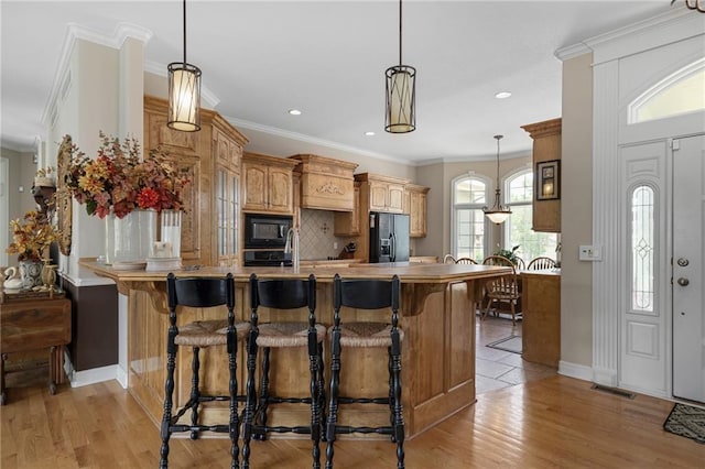 4148 SE Paddock Dr, Lees Summit, MO 64082 - kitchen featuring black appliances, a kitchen bar, light wood finished floors, crown molding, and a peninsula