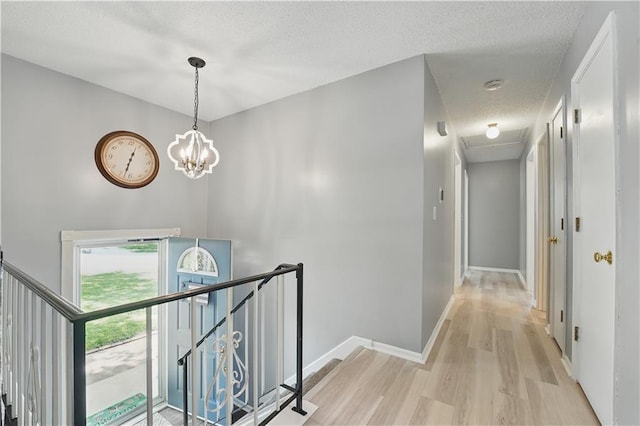 304 SE Moore St, Blue Springs, MO 64014 - hallway featuring an upstairs landing, light wood-style floors, a textured ceiling, and a chandelier