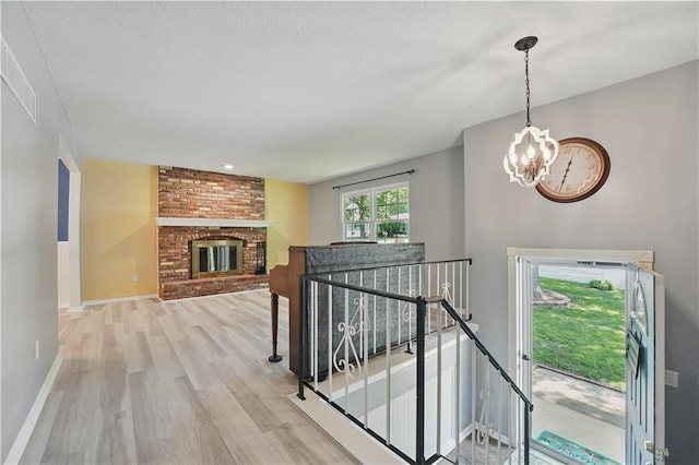 304 SE Moore St, Blue Springs, MO 64014 - staircase featuring wood finished floors, a chandelier, and a brick fireplace