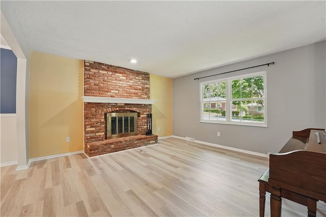 304 SE Moore St, Blue Springs, MO 64014 - living area featuring light wood finished floors, a brick fireplace, and a textured ceiling