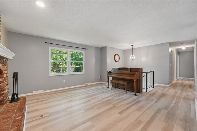 304 SE Moore St, Blue Springs, MO 64014 - living area with a textured ceiling, light wood-style flooring, a brick fireplace, and recessed lighting