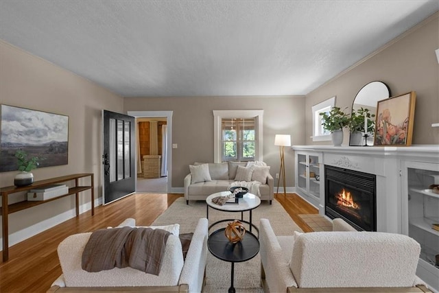 6424 Floyd St, Overland Park, KS 66202 - living room featuring light wood-style flooring, a glass covered fireplace, and ornamental molding
