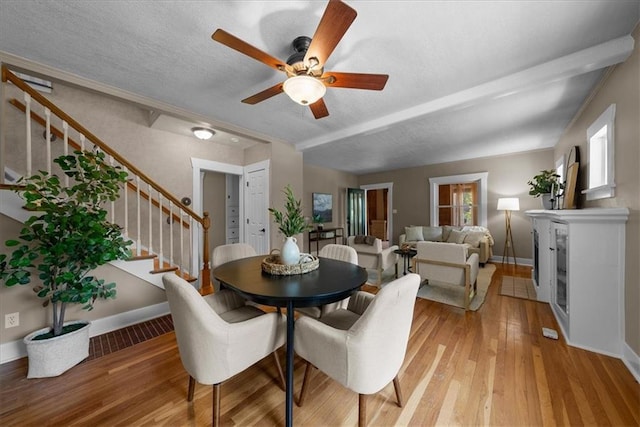 6424 Floyd St, Overland Park, KS 66202 - dining area featuring stairs, ceiling fan, light wood-style floors, a glass covered fireplace, and a textured ceiling