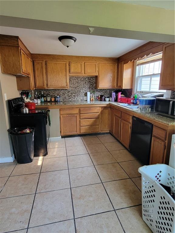 514 E Jackson Ave, Iola, KS 66749 - kitchen featuring black appliances, brown cabinetry, backsplash, and light tile patterned floors