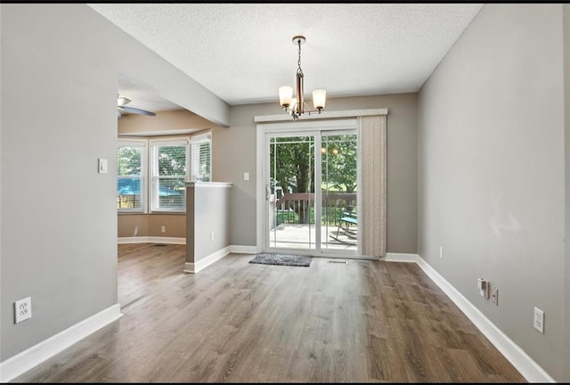 2541 NE Dale Hunter Ln, Lees Summit, MO 64086 - unfurnished dining area featuring a chandelier, wood finished floors, a textured ceiling, and a ceiling fan