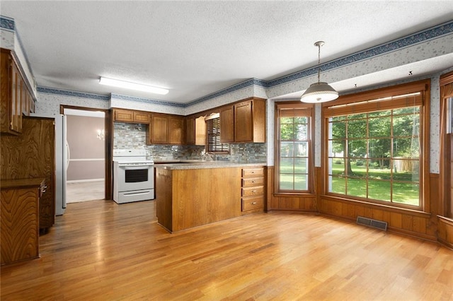 13220 W 76th St, Lenexa, KS 66216 - kitchen with white range with electric stovetop, wallpapered walls, light wood-style flooring, a peninsula, and a textured ceiling