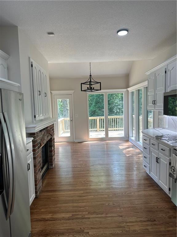 1411 NE 85th Ter, Kansas City, MO 64155 - kitchen featuring stainless steel fridge with ice dispenser, dark wood-type flooring, a fireplace, white cabinetry, and a textured ceiling