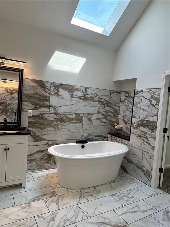 1411 NE 85th Ter, Kansas City, MO 64155 - full bath with tile walls, marble finish floors, vanity, a skylight, and a freestanding bath
