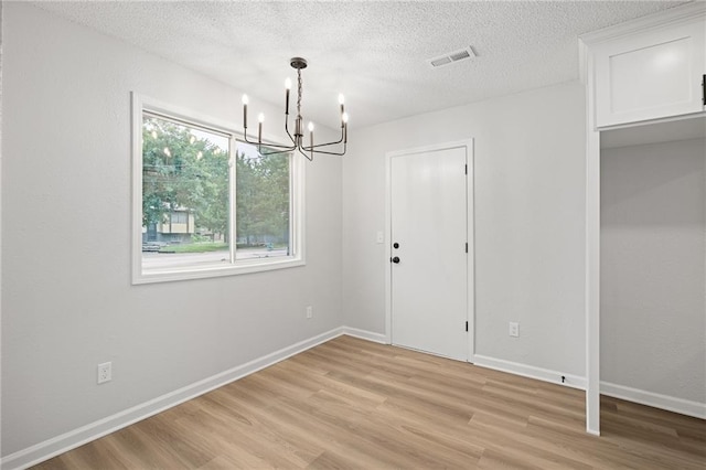 508 N Lincoln St, Olathe, KS 66061 - unfurnished dining area with a chandelier, light wood finished floors, and a textured ceiling