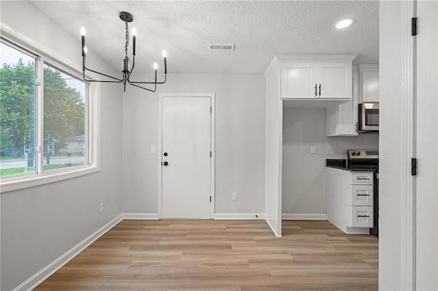 508 N Lincoln St, Olathe, KS 66061 - unfurnished dining area featuring healthy amount of natural light, a chandelier, a textured ceiling, light wood finished floors, and recessed lighting
