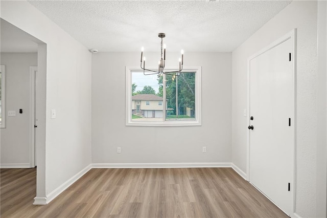 508 N Lincoln St, Olathe, KS 66061 - unfurnished dining area with light wood-style floors, a chandelier, and a textured ceiling