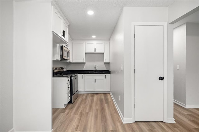 508 N Lincoln St, Olathe, KS 66061 - kitchen featuring appliances with stainless steel finishes, light wood-style floors, dark countertops, white cabinets, and recessed lighting