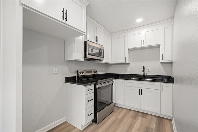 508 N Lincoln St, Olathe, KS 66061 - kitchen featuring stainless steel appliances, light wood finished floors, dark countertops, white cabinets, and a textured wall