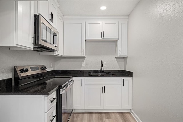 508 N Lincoln St, Olathe, KS 66061 - kitchen with appliances with stainless steel finishes, white cabinetry, light wood-style floors, dark stone counters, and a textured wall