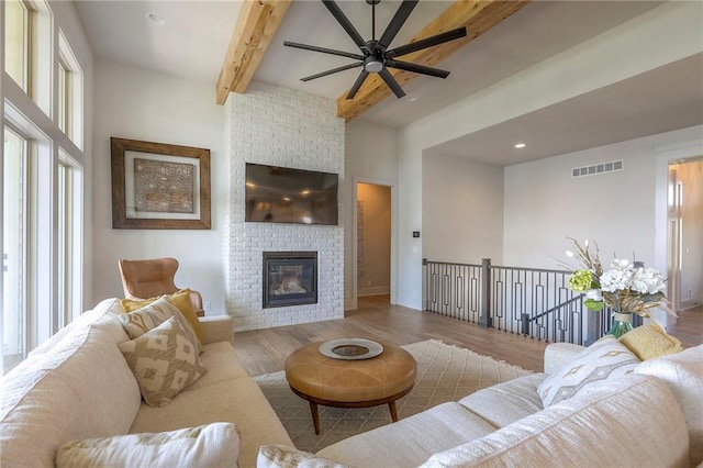 12605 W 169th St, Overland Park, KS 66221 - living area featuring plenty of natural light, a ceiling fan, wood finished floors, beamed ceiling, and a brick fireplace