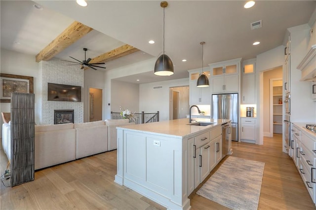 12605 W 169th St, Overland Park, KS 66221 - kitchen featuring stainless steel appliances, a ceiling fan, light wood-style floors, white cabinets, and beam ceiling