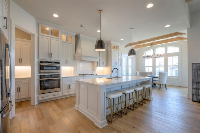 12605 W 169th St, Overland Park, KS 66221 - kitchen with custom exhaust hood, backsplash, stainless steel appliances, an island with sink, and light countertops
