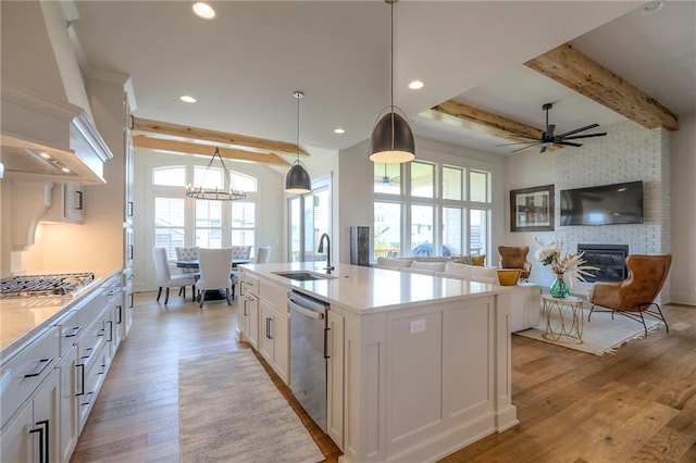 12605 W 169th St, Overland Park, KS 66221 - kitchen featuring appliances with stainless steel finishes, light wood finished floors, a brick fireplace, plenty of natural light, and beam ceiling