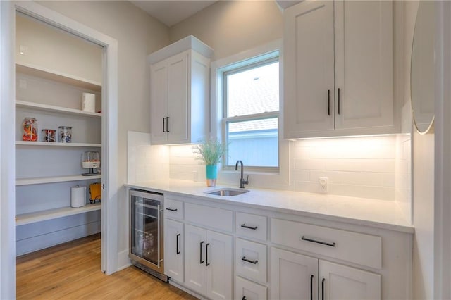 12605 W 169th St, Overland Park, KS 66221 - kitchen featuring wine cooler, white cabinets, light wood-type flooring, and tasteful backsplash