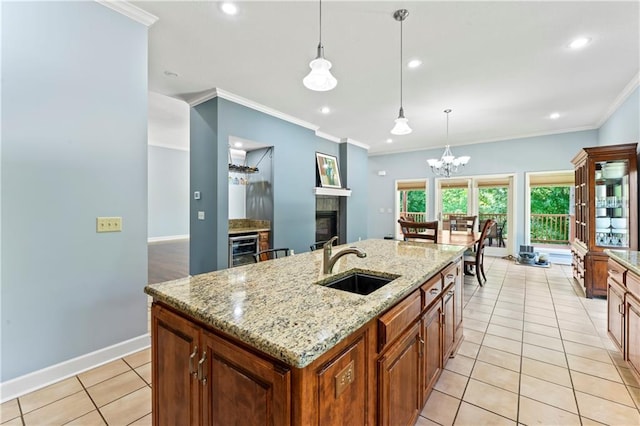 31134 W 161st St, Excelsior Springs, MO 64024 - kitchen featuring wine cooler, a glass covered fireplace, ornamental molding, a kitchen island with sink, and light tile patterned floors