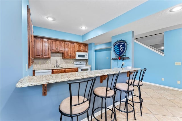 31134 W 161st St, Excelsior Springs, MO 64024 - kitchen featuring white appliances, a breakfast bar, backsplash, and light stone countertops