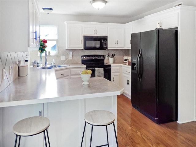 4301 NE 84th Ter, Kansas City, MO 64156 - kitchen featuring black appliances, a peninsula, light countertops, white cabinetry, and a breakfast bar