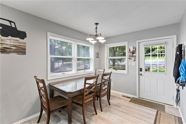 321 W Sugarlake Dr, Mound City, KS 66056 - dining room with a chandelier, light wood-style floors, and a textured ceiling
