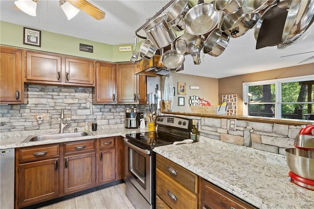 321 W Sugarlake Dr, Mound City, KS 66056 - kitchen with appliances with stainless steel finishes, decorative backsplash, a ceiling fan, brown cabinetry, and a textured ceiling