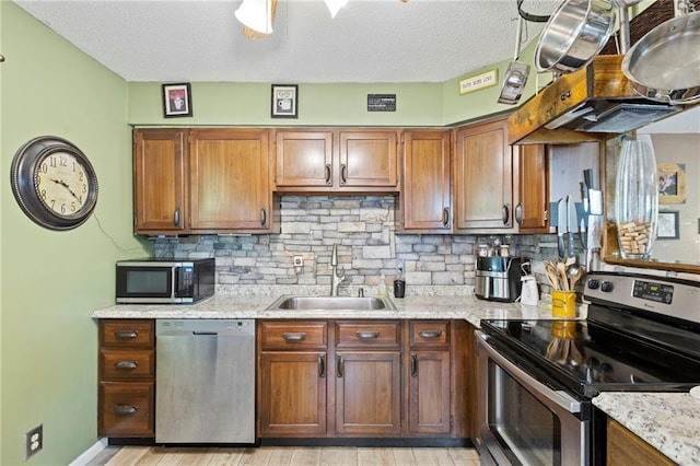 321 W Sugarlake Dr, Mound City, KS 66056 - kitchen with appliances with stainless steel finishes, light wood-style flooring, backsplash, a textured ceiling, and brown cabinets