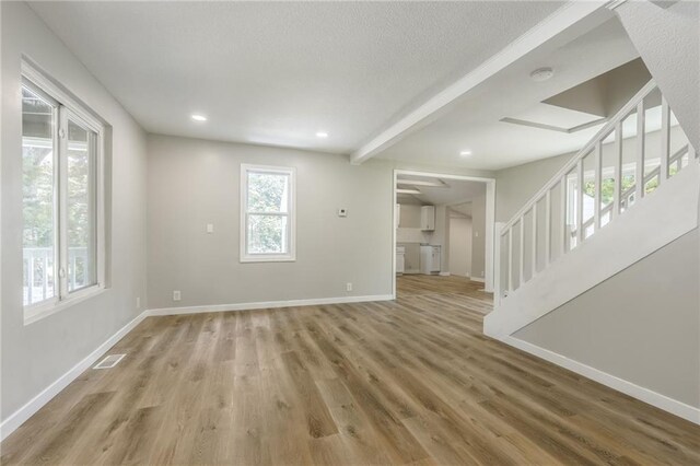 8801 E 49th St, Kansas City, MO 64129 - unfurnished living room featuring stairs, light wood-type flooring, recessed lighting, a textured ceiling, and beamed ceiling
