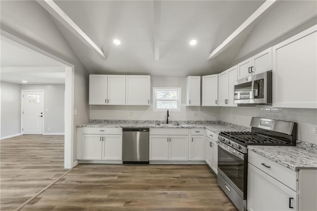 8801 E 49th St, Kansas City, MO 64129 - kitchen with appliances with stainless steel finishes, vaulted ceiling, white cabinets, light stone counters, and light wood-type flooring