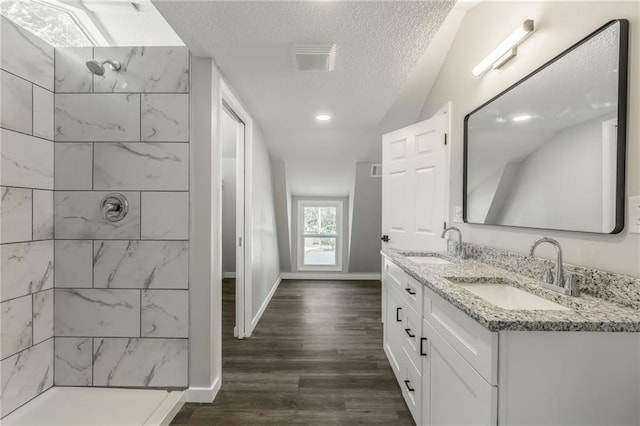 8801 E 49th St, Kansas City, MO 64129 - full bathroom featuring double vanity, a textured ceiling, a walk in shower, and wood finished floors