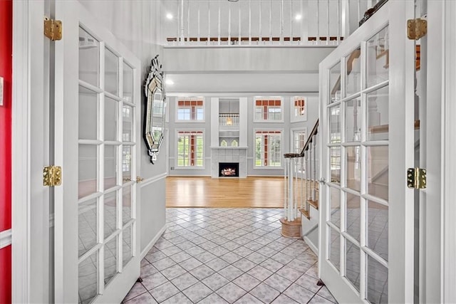 4328 W 110th St, Leawood, KS 66211 - entrance foyer featuring french doors, a warm lit fireplace, light tile patterned flooring, stairway, and a towering ceiling