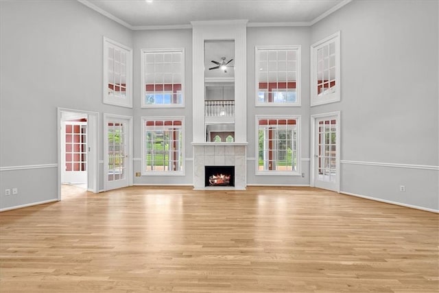 4328 W 110th St, Leawood, KS 66211 - unfurnished living room featuring a towering ceiling, plenty of natural light, light wood-style floors, ornamental molding, and a tile fireplace