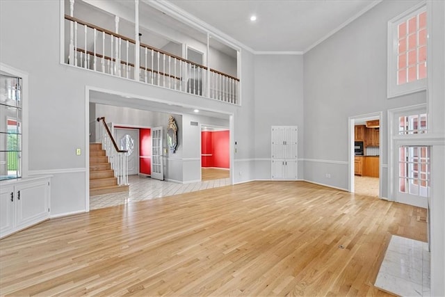 4328 W 110th St, Leawood, KS 66211 - unfurnished living room featuring a towering ceiling, crown molding, wood finished floors, stairway, and recessed lighting