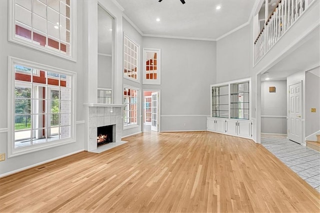 4328 W 110th St, Leawood, KS 66211 - unfurnished living room featuring a towering ceiling, wood finished floors, crown molding, a tiled fireplace, and ceiling fan