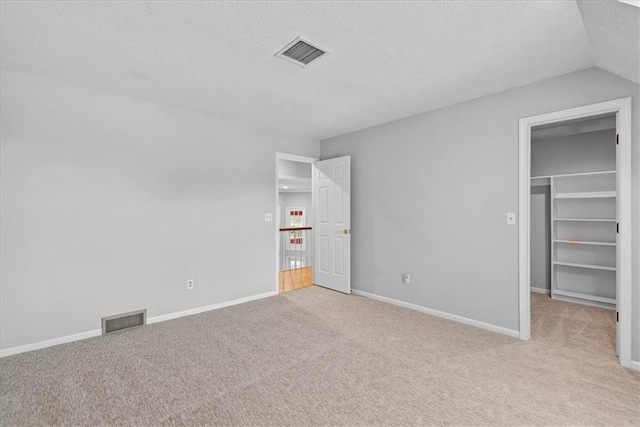 4328 W 110th St, Leawood, KS 66211 - unfurnished bedroom featuring a textured ceiling, light colored carpet, a walk in closet, and a closet