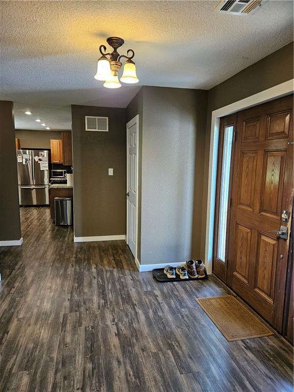 245 S 250th St, Pittsburg, KS 66762 - foyer entrance featuring dark wood-style flooring, a textured ceiling, and a chandelier