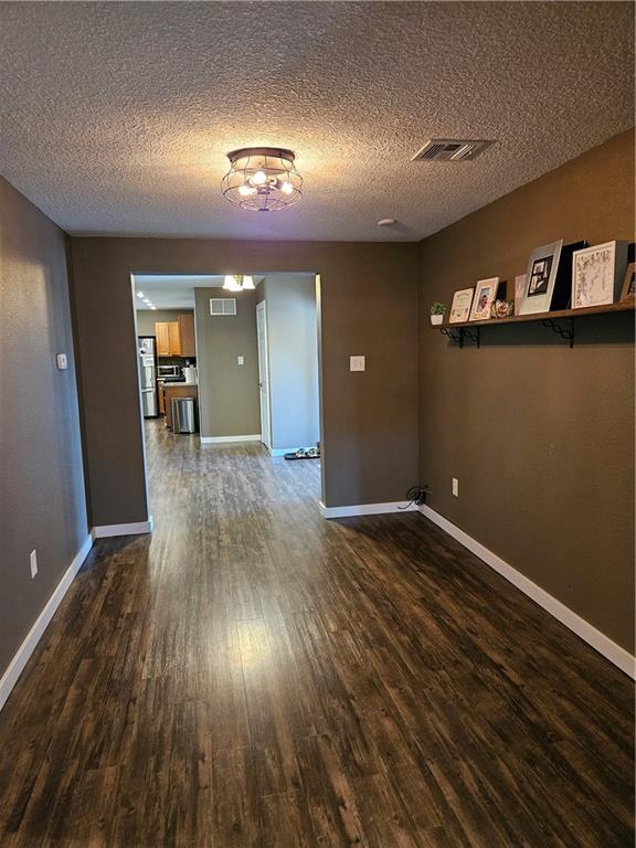 245 S 250th St, Pittsburg, KS 66762 - unfurnished room with wood finished floors, a textured ceiling, and a chandelier