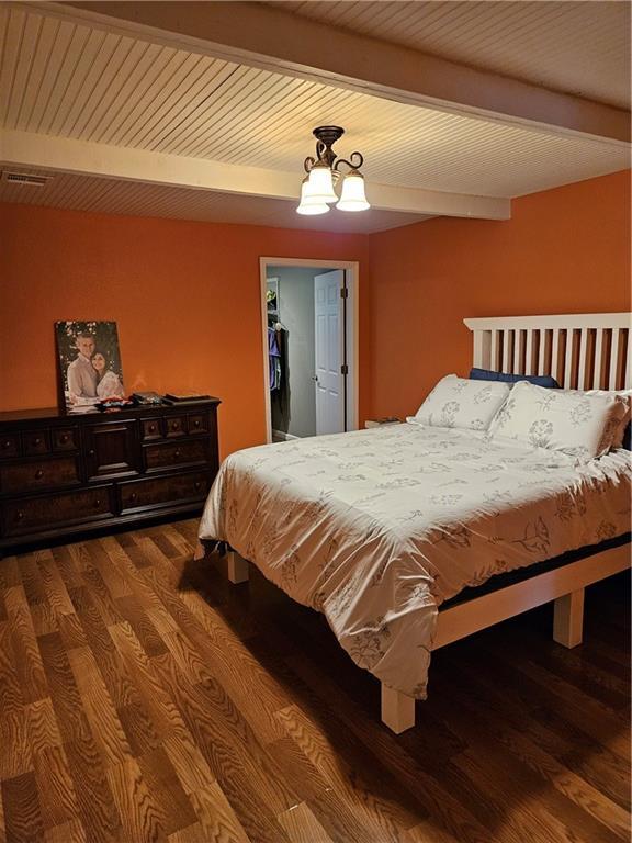 245 S 250th St, Pittsburg, KS 66762 - bedroom featuring beamed ceiling, wood finished floors, a walk in closet, and a chandelier