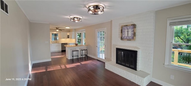 8738 Horton St, Overland Park, KS 66207 - living area featuring dark wood-style floors, ornamental molding, a fireplace, and a ceiling fan