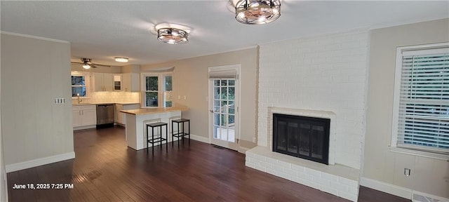 8738 Horton St, Overland Park, KS 66207 - living room with dark wood-style floors, a fireplace, ornamental molding, and a ceiling fan