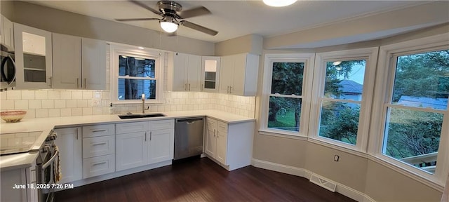 8738 Horton St, Overland Park, KS 66207 - kitchen with stainless steel appliances, dark wood-style floors, decorative backsplash, glass insert cabinets, and white cabinetry