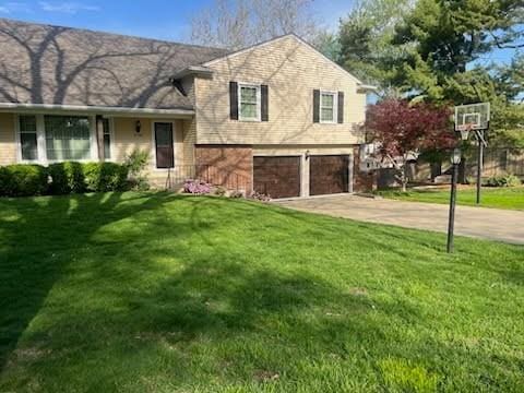 8738 Horton St, Overland Park, KS 66207 - split level home with a garage, a front lawn, and driveway