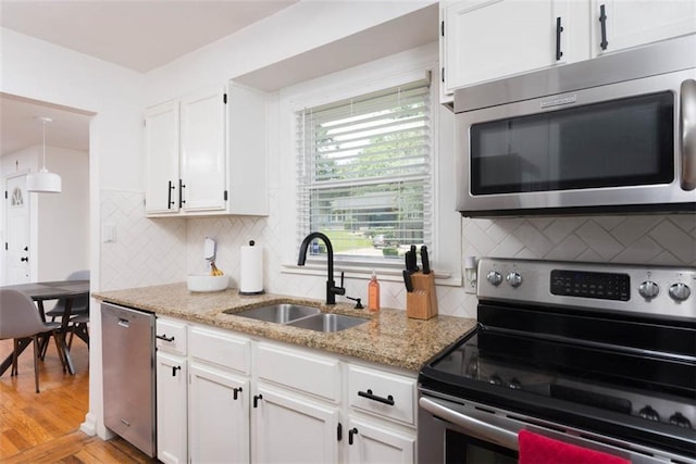 5915 Fontana St, Fairway, KS 66205 - kitchen featuring stainless steel appliances, white cabinets, light stone countertops, tasteful backsplash, and light wood-style flooring