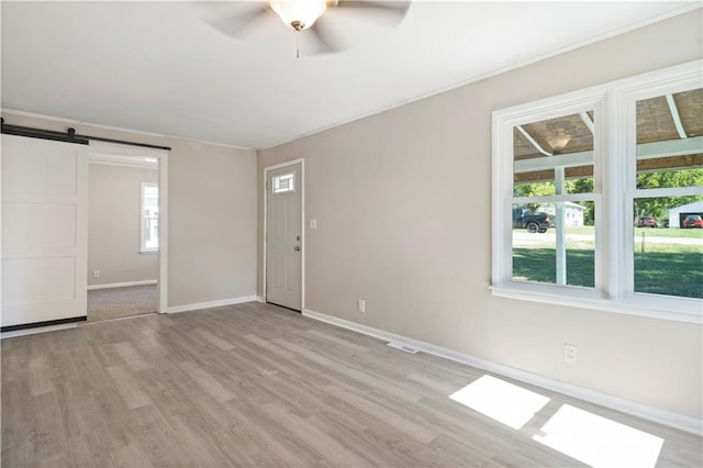 15309 E Mayes Rd, Independence, MO 64050 - empty room featuring a barn door, a ceiling fan, and light wood-style flooring