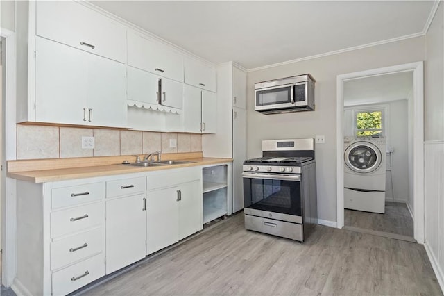 15309 E Mayes Rd, Independence, MO 64050 - kitchen featuring stainless steel appliances, open shelves, washer / clothes dryer, light wood finished floors, and ornamental molding