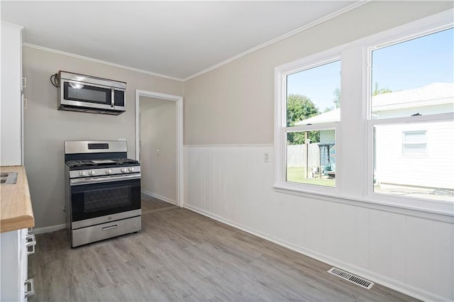 15309 E Mayes Rd, Independence, MO 64050 - kitchen featuring appliances with stainless steel finishes, wood finished floors, plenty of natural light, crown molding, and wainscoting