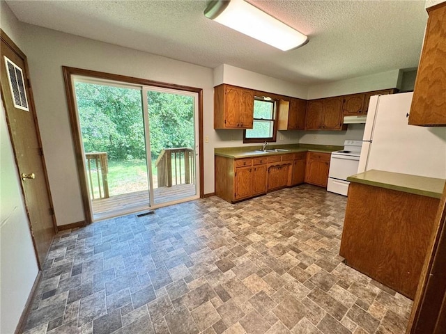 177 SE 411th Rd, Warrensburg, MO 64093 - kitchen featuring white appliances, under cabinet range hood, stone finish flooring, a textured ceiling, and brown cabinetry